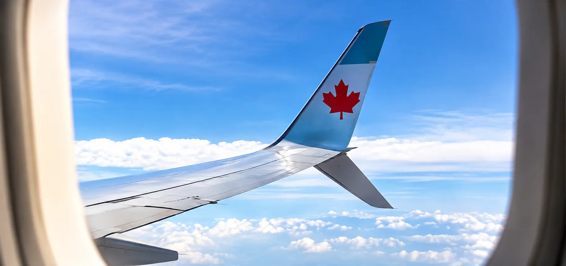 Vue d’une aile d’avion avec une feuille d’érable canadienne pour l’immigration temporaire au Canada